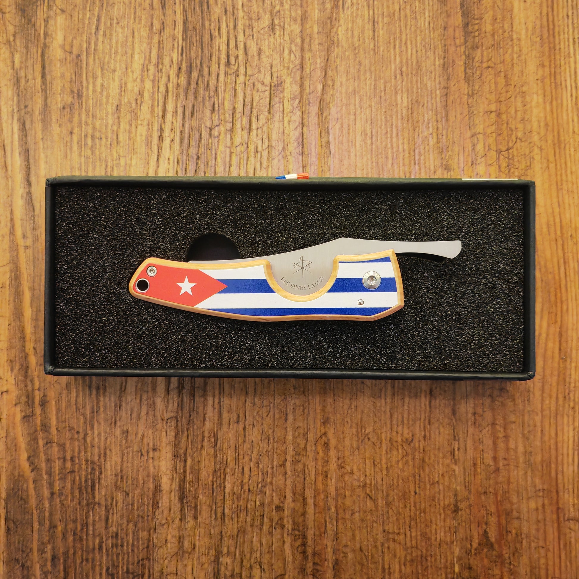 Folding knife with a flag design on a wooden surface