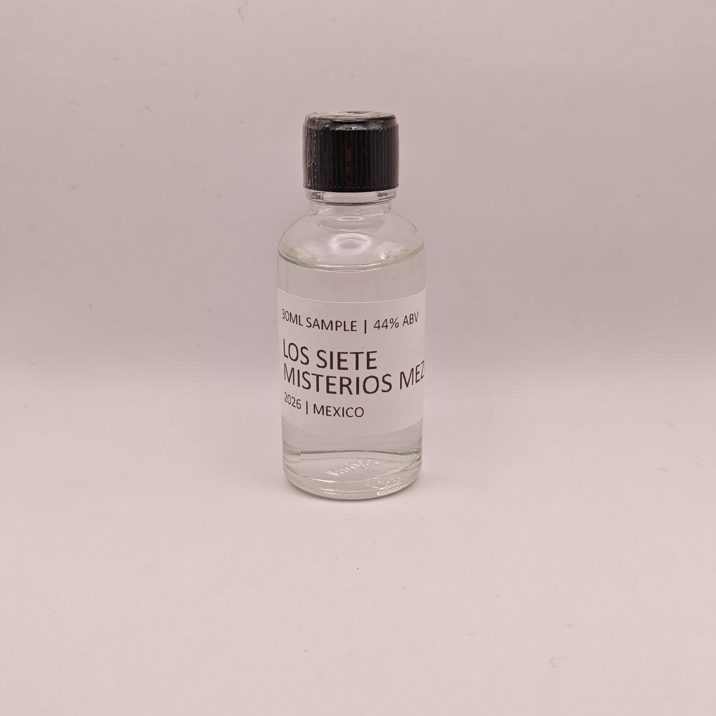 Small bottle of Los Siete Misterios Mezcal on a light gray background