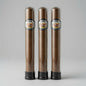 Three cigars in clear glass tubes with black bases, standing side by side on a light gray background. Each tube has a circular label reading 'Cigar Makers' and '70% Arabica'.