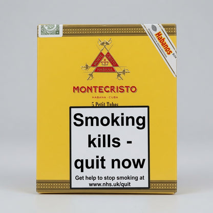 A yellow Montecristo Habanos cigar box with a large white warning label reading 'Smoking kills - quit now' on the front, photographed against a light gray studio background.