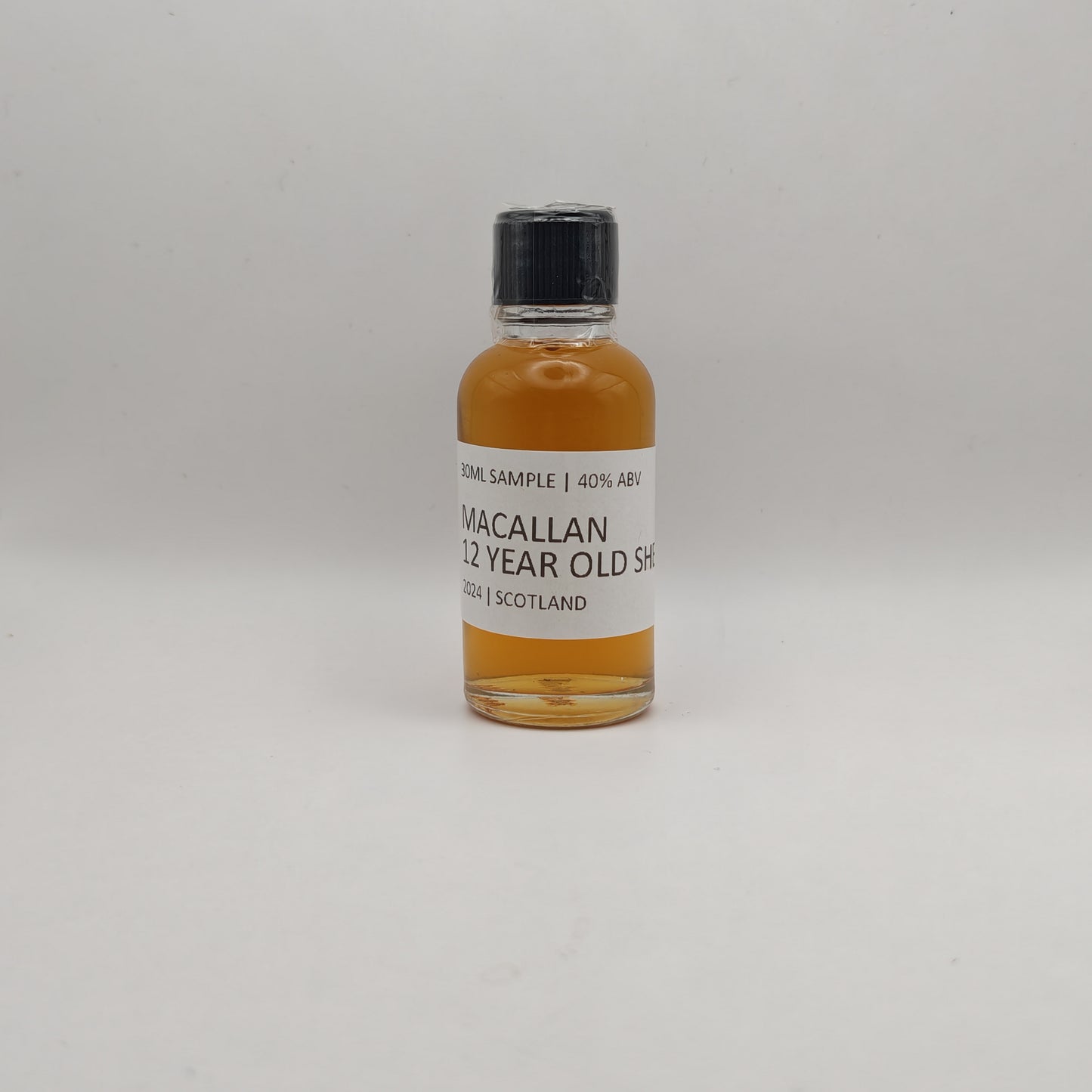Small bottle of Macallan 12 Year Old Sherry whisky sample on a white background