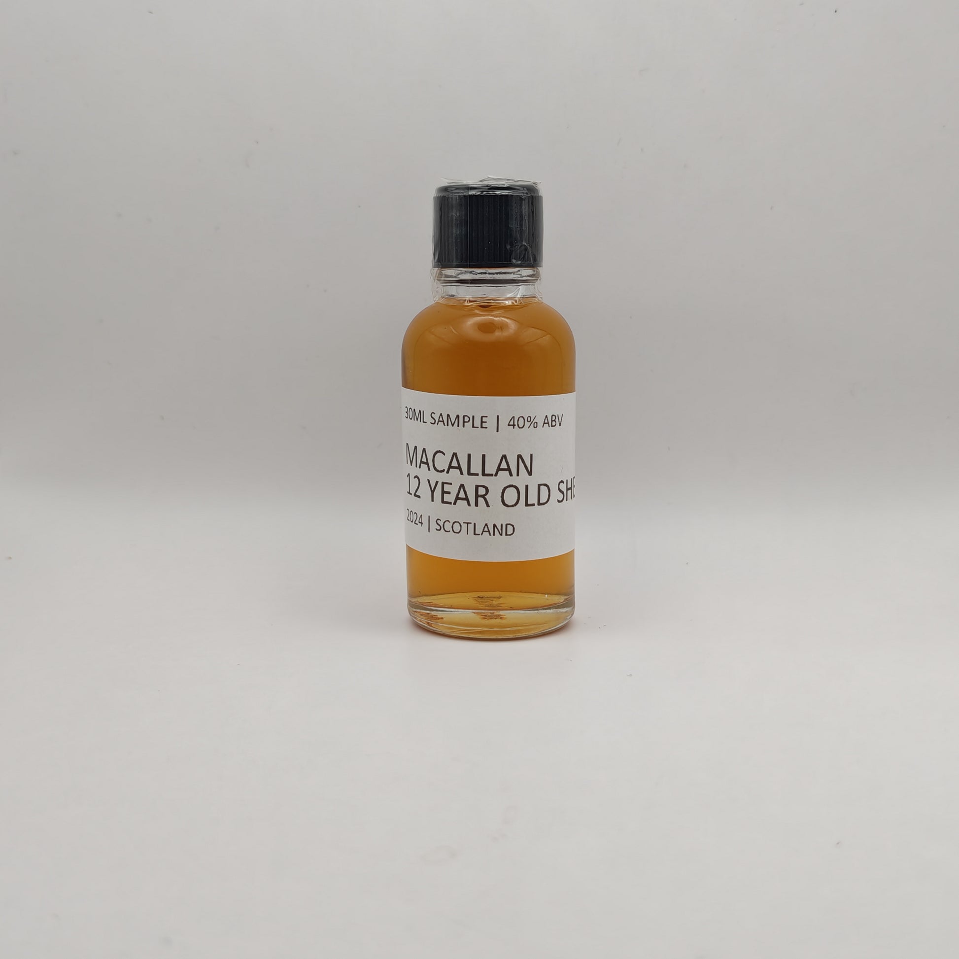 Small bottle of Macallan 12 Year Old Sherry whisky sample on a white background