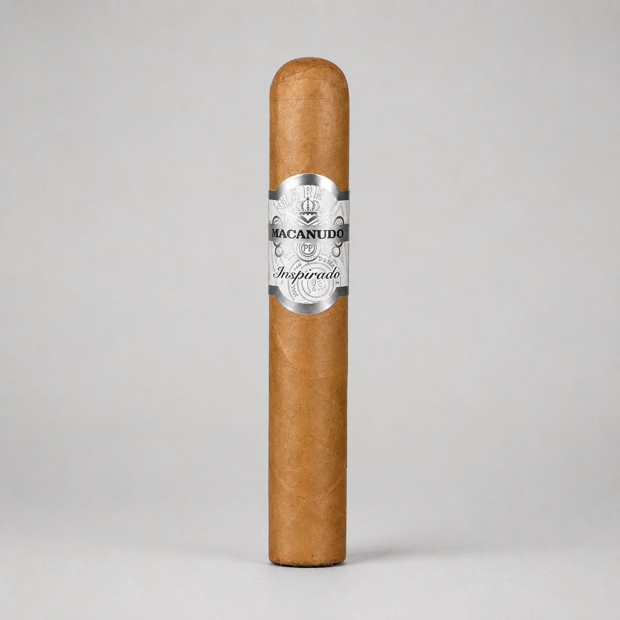 A single Macanudo Aspirado cigar standing upright on a light gray background, featuring a silver and black paper band with the brand name and 'Aspirado' written on it.