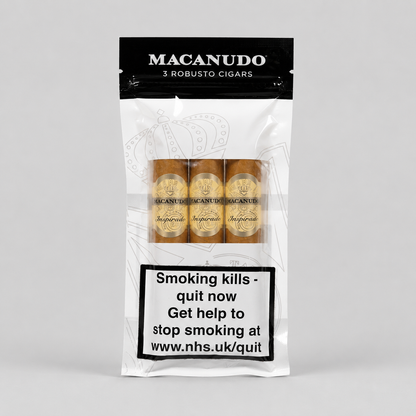 A package of Macanudo 3 Robusto Cigars on a light gray background. The white and black resealable pouch shows three cigars through a clear window, with a prominent smoking health warning label on the lower half.