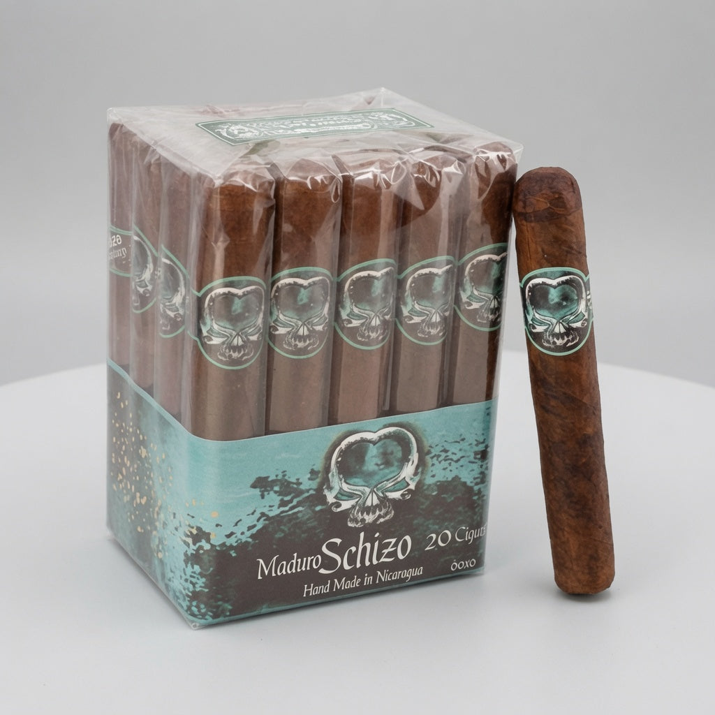 A box of Maduro Schizo 20 cigars with one single cigar placed beside it on a light gray studio background. The cigars are brown, and the packaging features a teal and brown design with a skull logo.