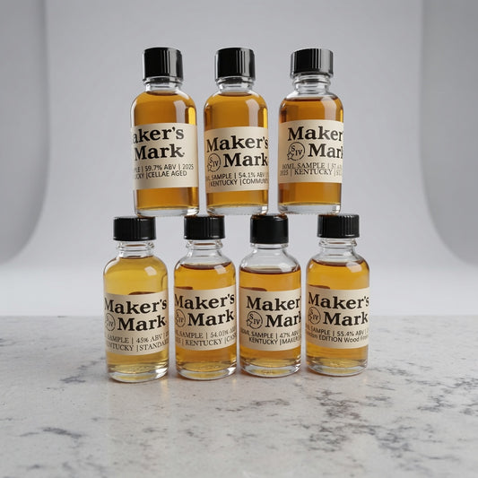 Multiple bottles of Maker's Mark whiskey arranged on a marble surface with a neutral background.