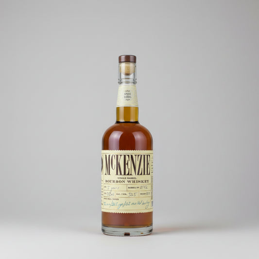 A bottle of McKenzie Single Barrel Bourbon Whiskey with amber liquid, a cream-colored label, and a brown cap, shown against a plain white background.