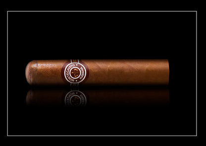 A single brown cigar with a circular silver and black band reading 'Cigarrito de la Hacienda', positioned horizontally against a solid black background with a subtle reflection below.