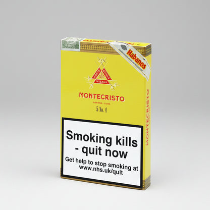 A pack of Montecristo Habanos cigars on a plain white background. The packaging is primarily yellow with a large white warning label on the front that reads 'Smoking kills - quit now' and includes the NHS website.