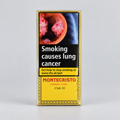 A rectangular cigarillo pack with a gold border, featuring a smoking-related health warning image and the Montecristo brand name on a light gray studio background.
