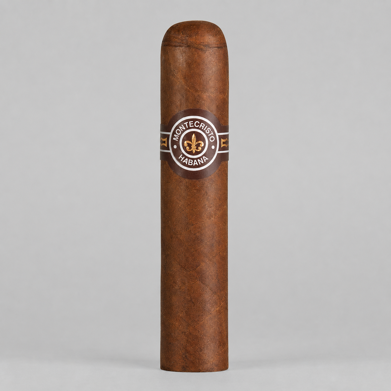 A single Montecristo Habana cigar standing upright against a neutral light gray background. The cigar has a rich medium-brown textured wrapper and features a circular brown paper band with gold and white details displaying the Montecristo logo.