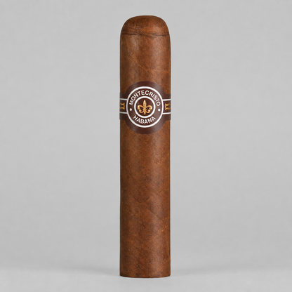 A single Montecristo Habana cigar standing upright against a neutral light gray background. The cigar has a rich medium-brown textured wrapper and features a circular brown paper band with gold and white details displaying the Montecristo logo.