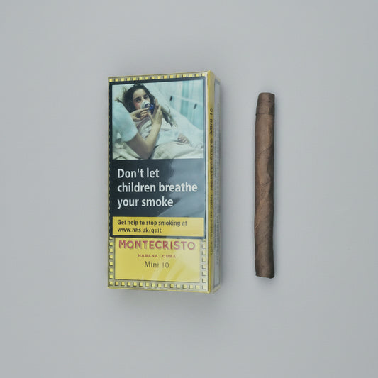 A Montecristo Marana Copa Mini 10 cigarette pack with a prominent smoking warning label, shown next to a single brown cigar on a solid taupe background.