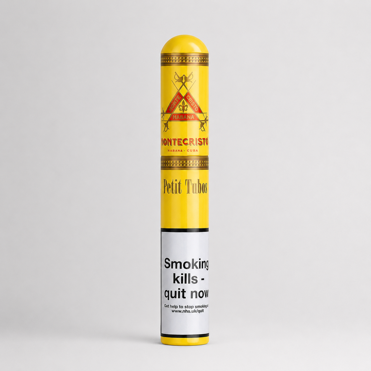 A single Montecristo Petit Tubo cigar in its original paper wrapper, standing vertically against a light gray studio background. The wrapper is bright yellow with red and gold printed details and a white health warning label near the bottom.