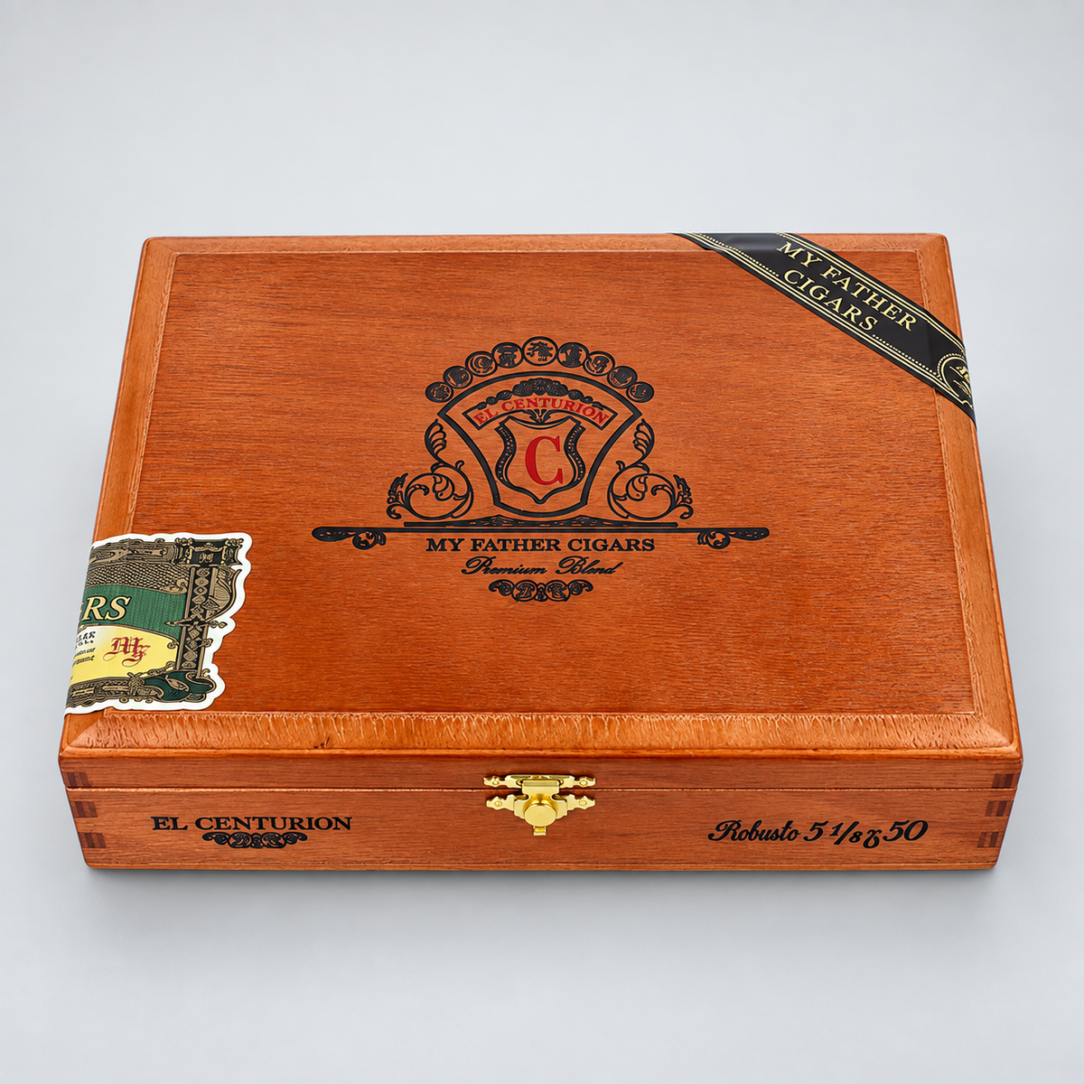 A wooden cigar humidor box with a warm reddish-brown finish, featuring the 'My Father Cigars' crest on top, a gold clasp, and branded bands on the lid, photographed on a light gray background.