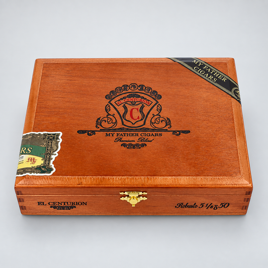 A wooden cigar humidor box with a warm reddish-brown finish, featuring the 'My Father Cigars' crest on top, a gold clasp, and branded bands on the lid, photographed on a light gray background.