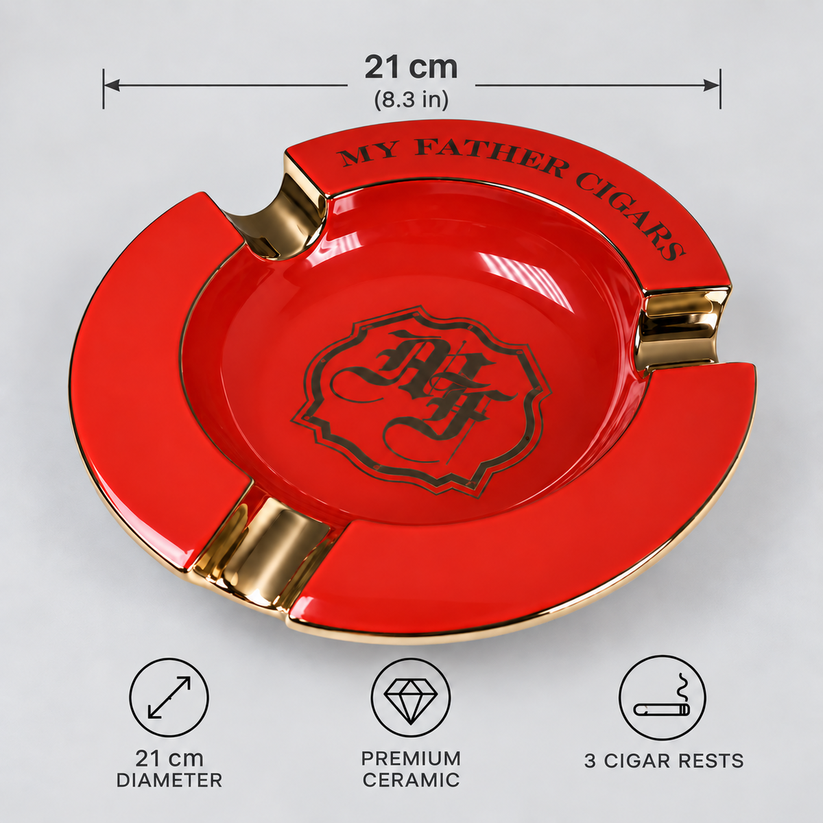 Red and gold ceramic cigar ashtray with three cigar rests, featuring a black gothic crest in the center and 'MY FATHER CIGARS' text on the rim. The image includes dimension annotations showing a 21 cm diameter and feature icons for premium ceramic and 3 cigar rests.