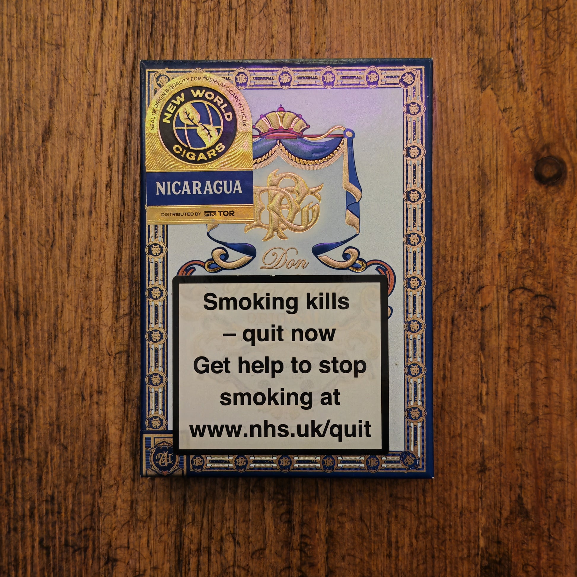 Cigar box with branding and health warning message on a wooden surface