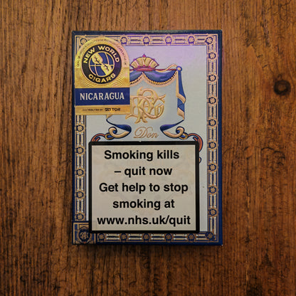 Cigar box with branding and health warning message on a wooden surface