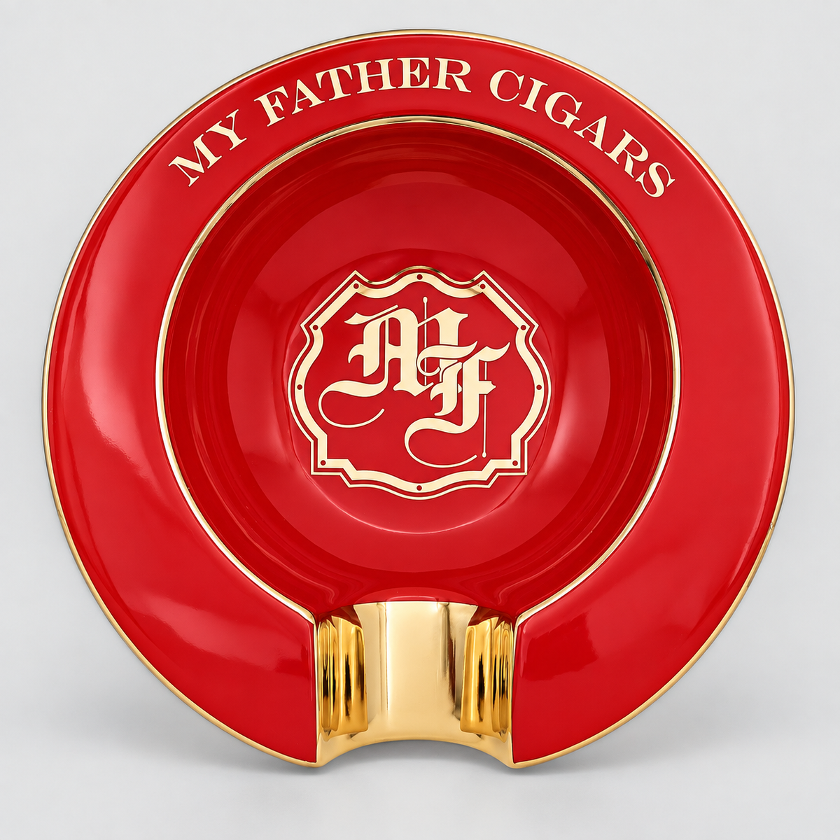 A red and gold ceramic cigar ashtray with a glossy finish, featuring the text 'MY FATHER CIGARS' and a central monogram crest.