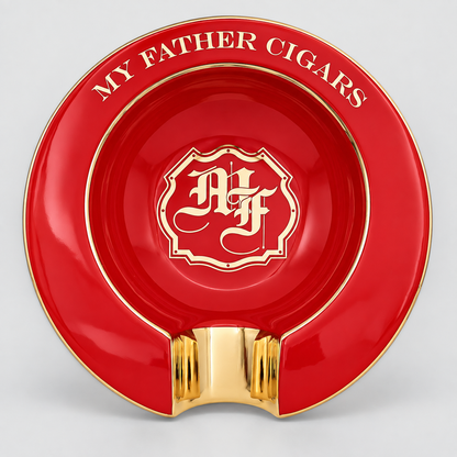 A red and gold ceramic cigar ashtray with a glossy finish, featuring the text 'MY FATHER CIGARS' and a central monogram crest.