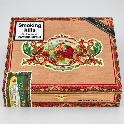 A wooden cigar box labeled 'Flor de las Antillas' by My Father Cigars, shown on a light gray background. The box has ornate red and gold decorative borders, a large central illustrated label, a black diagonal ribbon reading 'MY FATHER CIGARS,' a white square panel with a smoking-health warning sticker, and a small side sticker.