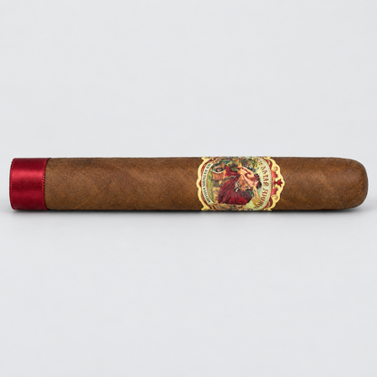 A single brown cigar with a red satin band on one end and a detailed vintage-style label in the center, photographed horizontally against a light gray background.