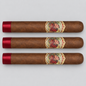 Three brown cigars arranged horizontally on a light gray background, each with a red satin tip and a decorative circular band featuring a portrait.