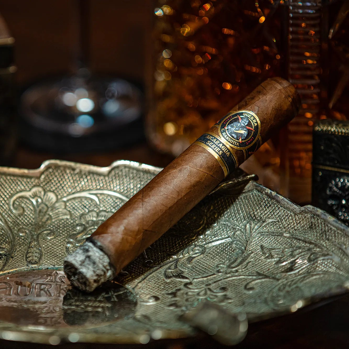 Cigar on an ornate metal tray with a blurred background