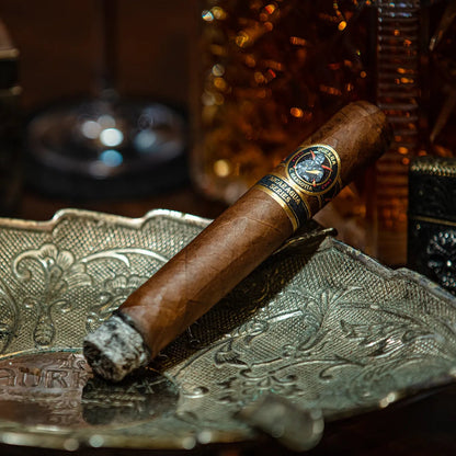 Cigar on an ornate metal tray with a blurred background