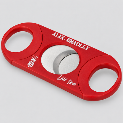 A red cigar cutter with silver stainless steel blades, featuring custom white printed text reading 'ALEC BRADLEY' and 'Live True' on a light gray background.