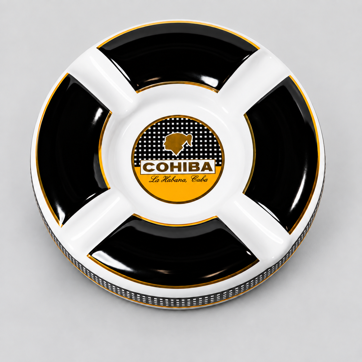 A round black and white divided cigar ashtray with gold trim, featuring a central logo for 'COHIBA La Habana Club'.