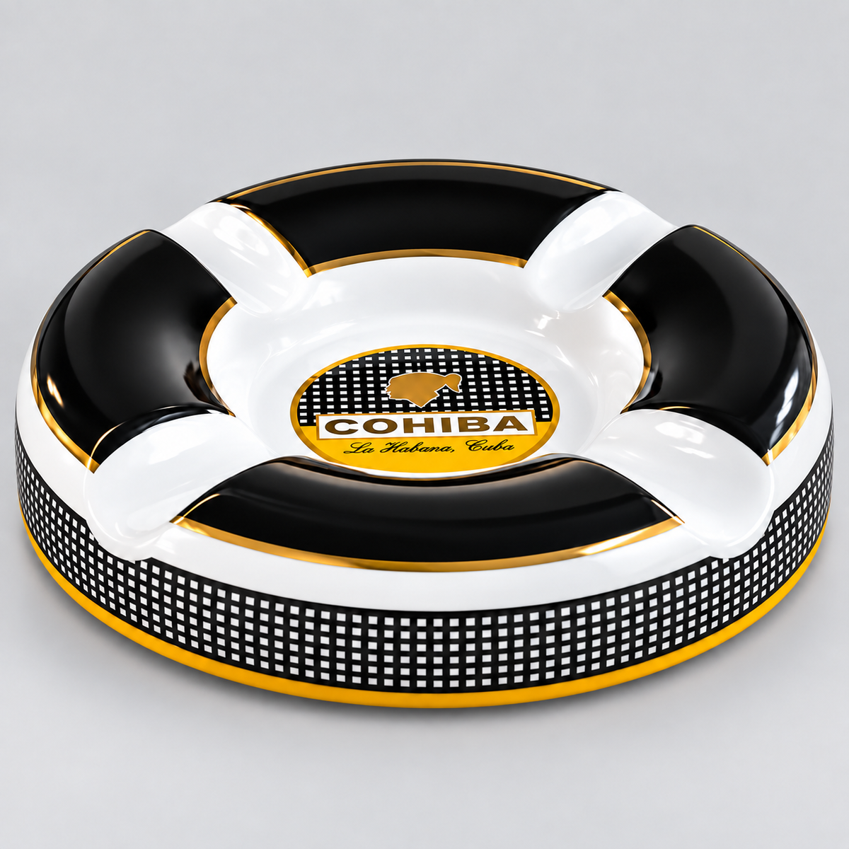 A circular black and white ashtray with gold trim, featuring a central logo for 'COHIBA The Premium Cigars' and a black-and-white checkered band around the lower edge, photographed on a light gray background.