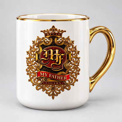 A white ceramic mug with a gold rim and handle, featuring a decorative gold crest with a red banner that reads 'MY FATHER CIGARS'.