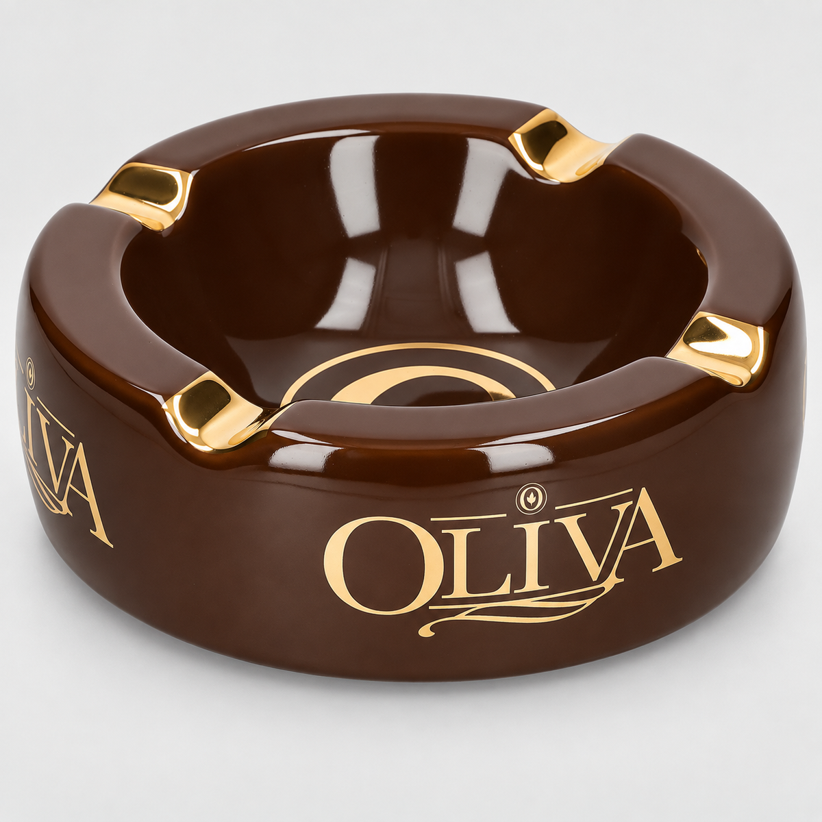 A glossy dark brown ceramic ashtray with gold accents and the brand name 'OLIVA' printed in gold on the front, set against a light gray background.