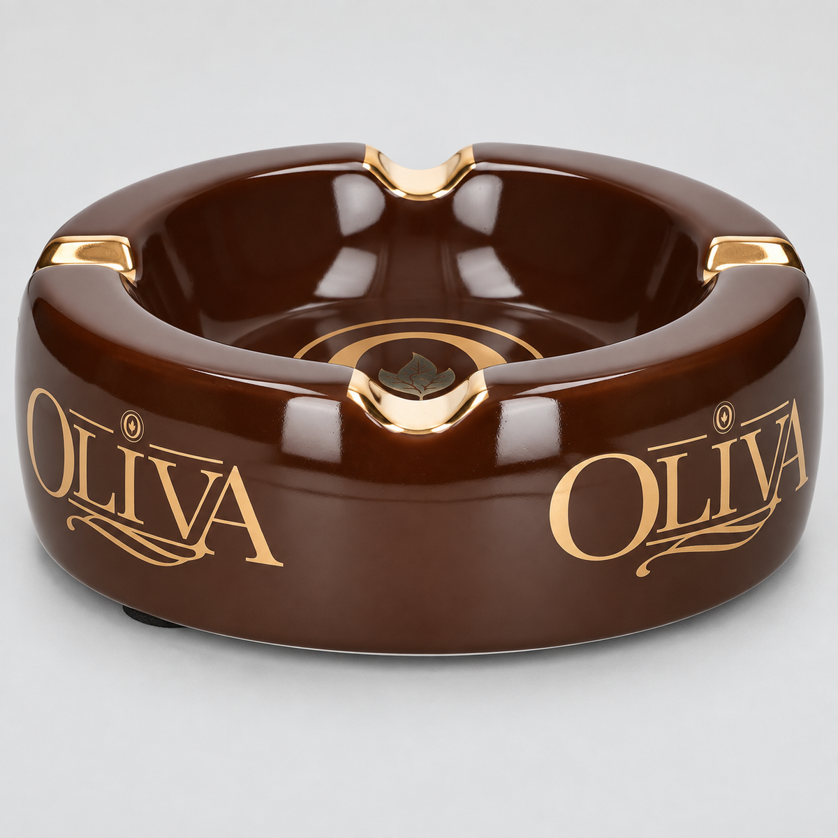 A glossy dark brown ceramic ashtray with gold accents and the brand name 'OLIVA' printed in gold on both sides, shown on a light gray background.
