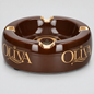 A glossy dark brown ceramic ashtray with gold accents and the brand name 'OLIVA' printed in gold on both sides, shown on a light gray background.