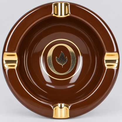 A round glossy brown ceramic ashtray with polished gold-tone accents, including three mounting slots and a central circular emblem featuring a leaf.