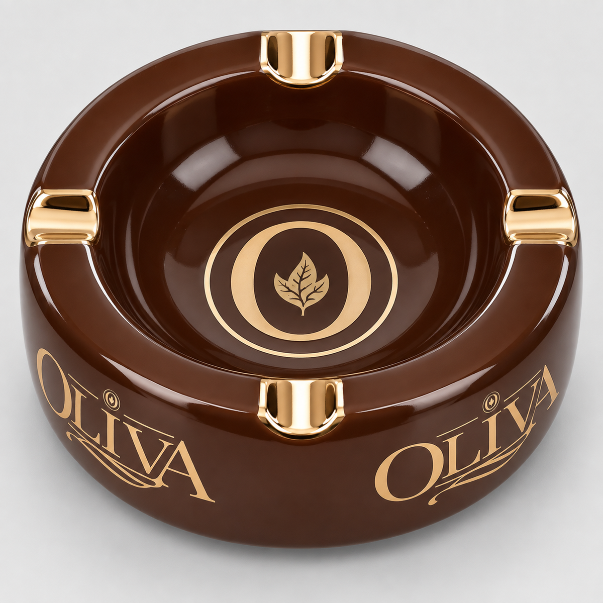 A glossy dark brown oval ashtray with four gold-tone metal anchor-style sockets and gold 'OLIVA' lettering on the sides, shown on a light gray background.