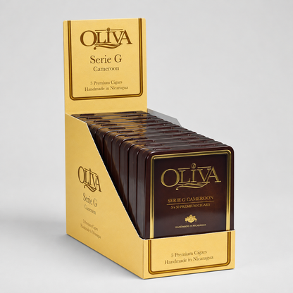 A display box of OLIVA Serie G Cameroón cigars, showing multiple packs of dark brown cigars with gold foil labels inside a gold-colored cardboard counter display.