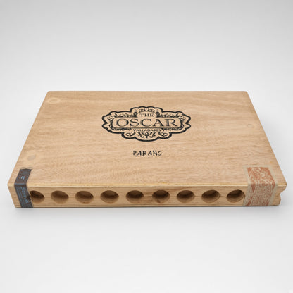 A rectangular wooden cigar storage box with a light natural wood finish, featuring a black engraved crest that reads 'The Oscar Valentino Habanco' and the word 'HABANCO' below it. The box has circular cutouts along the bottom edge and a decorative paper band on the right side, photographed on a clean white background.