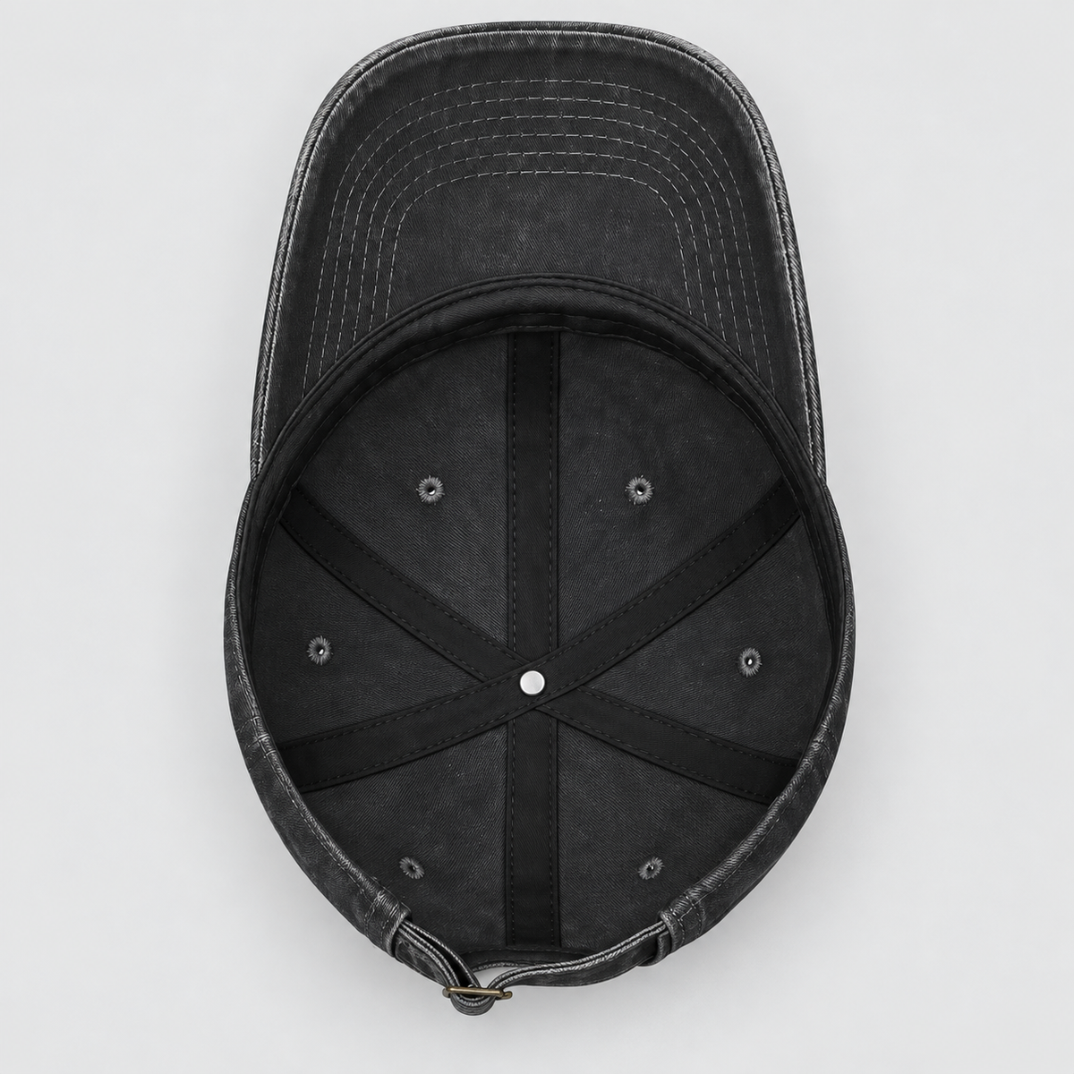 A top-down view of a washed black baseball cap, showing the curved brim, black stitched interior panels, and ventilation eyelets on a light gray background.