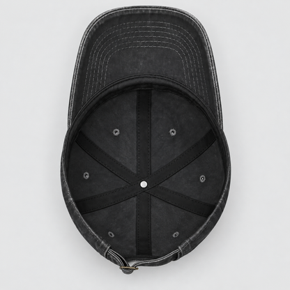 A top-down view of a washed black baseball cap, showing the curved brim, black stitched interior panels, and ventilation eyelets on a light gray background.