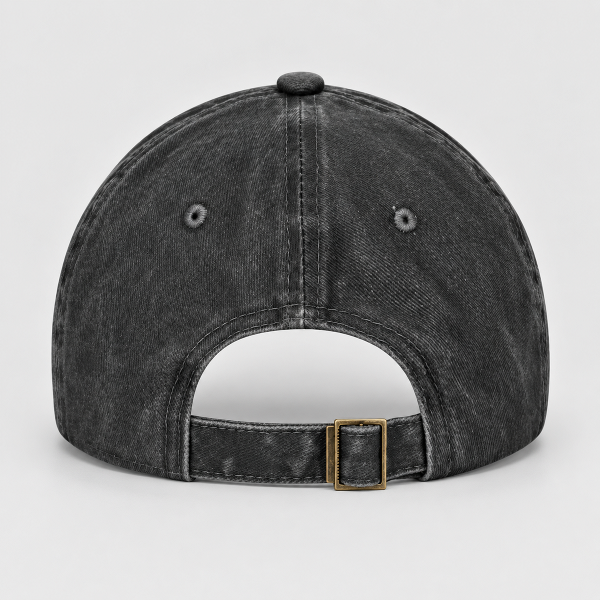 The back of a washed black baseball cap with an adjustable strap and a gold-tone metal buckle, shown on a light gray background.