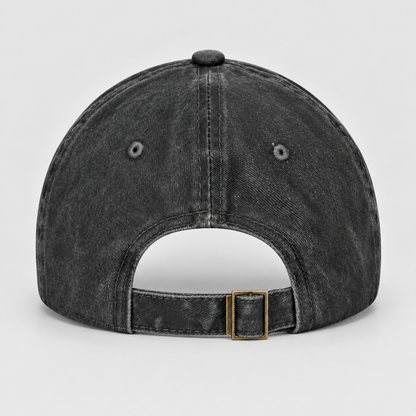The back of a washed black baseball cap with an adjustable strap and a gold-tone metal buckle, shown on a light gray background.