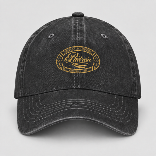 A black washed baseball cap with a gold embroidered oval logo on the front that reads 'Madron Family Farm' and 'Falcone & Smith'.