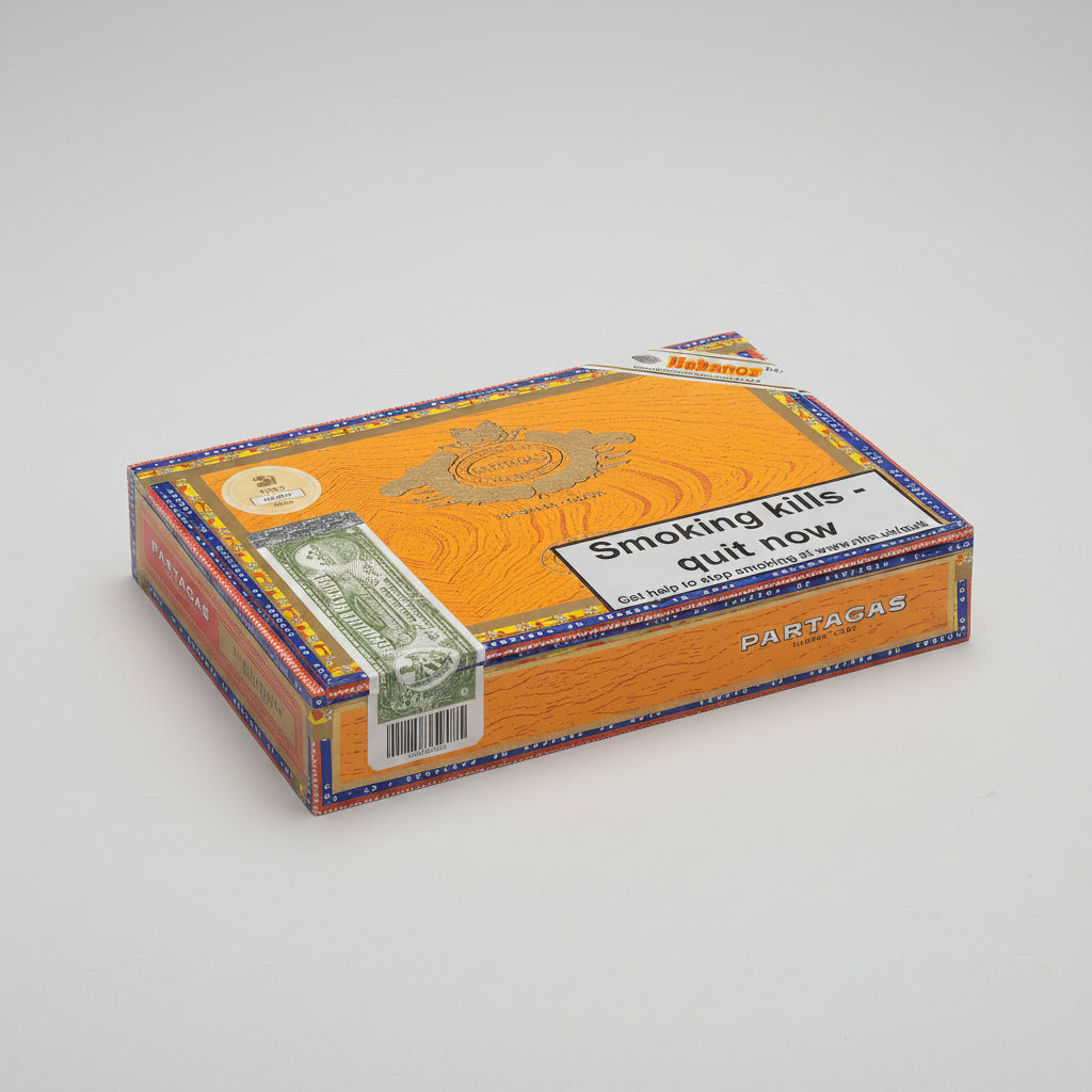 A Habanos Partagas cigar box with a prominent warning label that reads 'Smoking kills - quit now'. The box features a golden-yellow wood-grain pattern with blue and red decorative borders, and a green dollar bill graphic on the side.