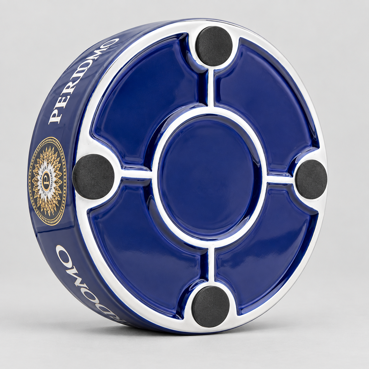 A circular blue and white ceramic ashtray with four black rubber feet, shown on a light gray background. The side of the ashtray features the brand name 'PERIDMO' in white text alongside a gold and black emblem.