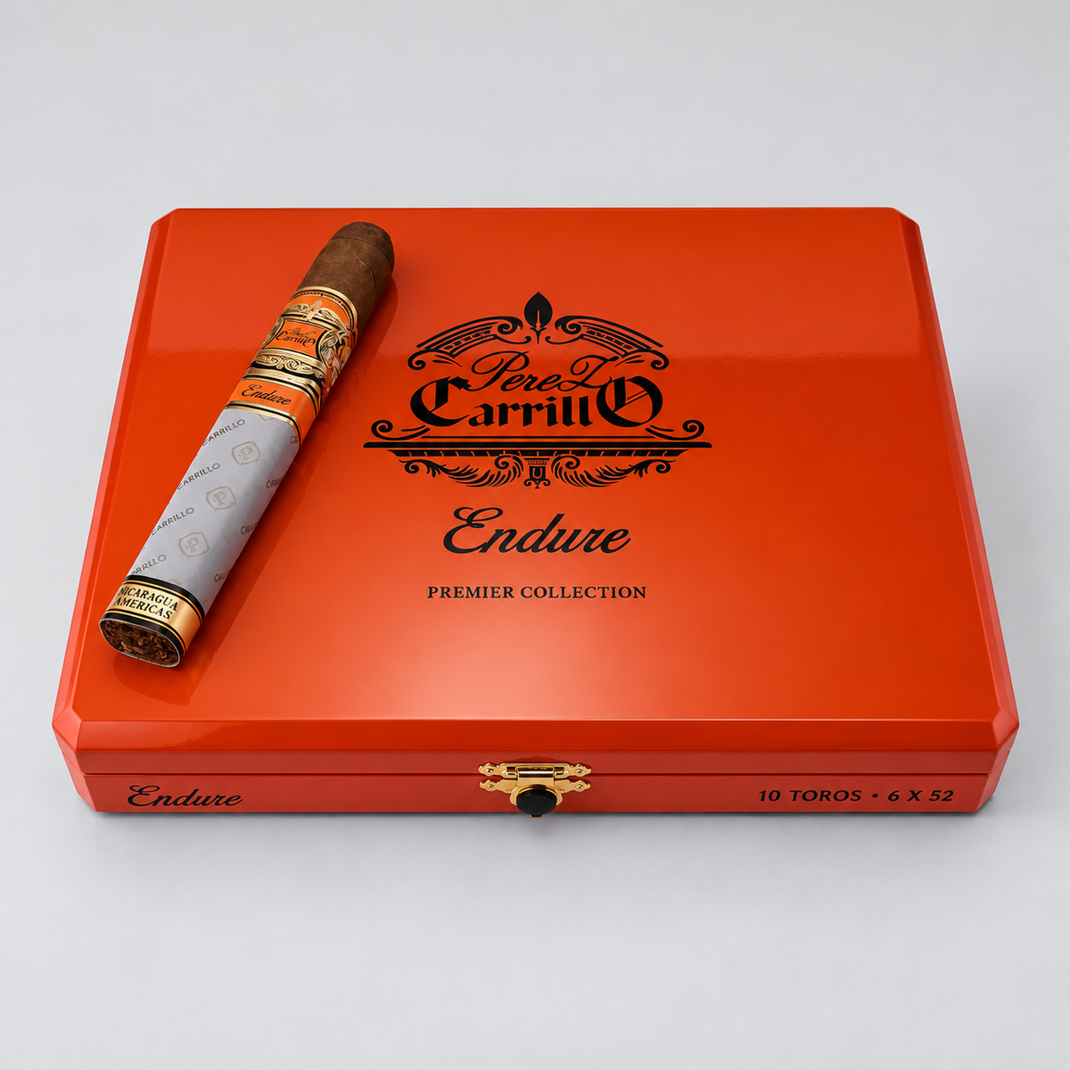 A red cigar presentation box with a gold clasp, featuring the black printed logo 'Perez Carrillo Endure Premier Collection' and a single cigar placed diagonally on top, photographed on a light gray background.