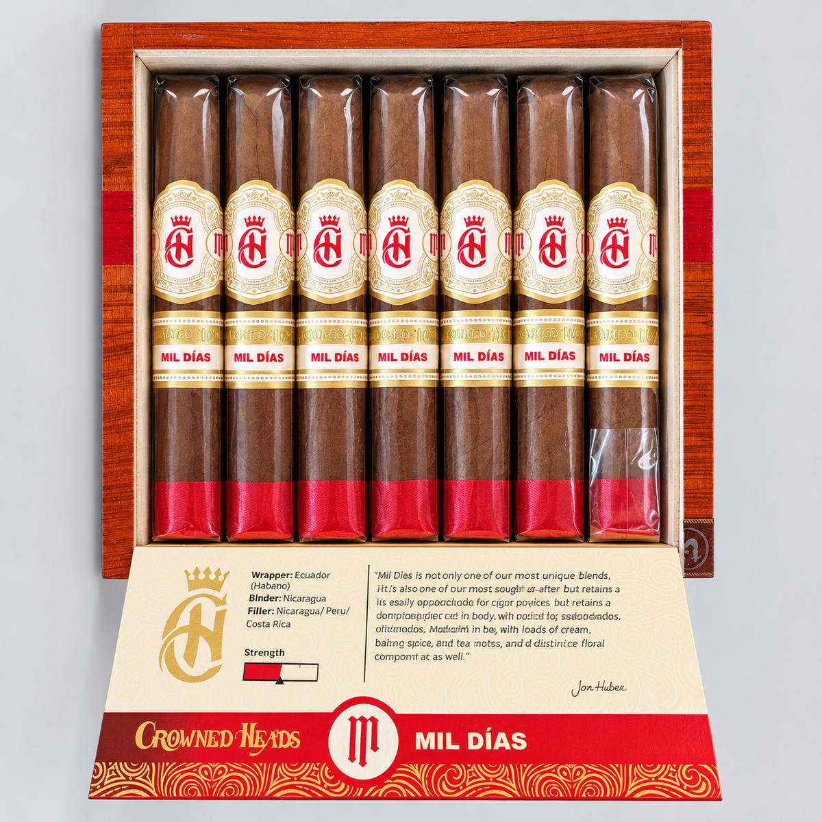 An open wooden cigar box containing eight cigars, with the left cigar removed to show the inner packaging and printed insert. The cigars have brown wrappers with cream and red labels reading 'CRONOS MIL DIAS.